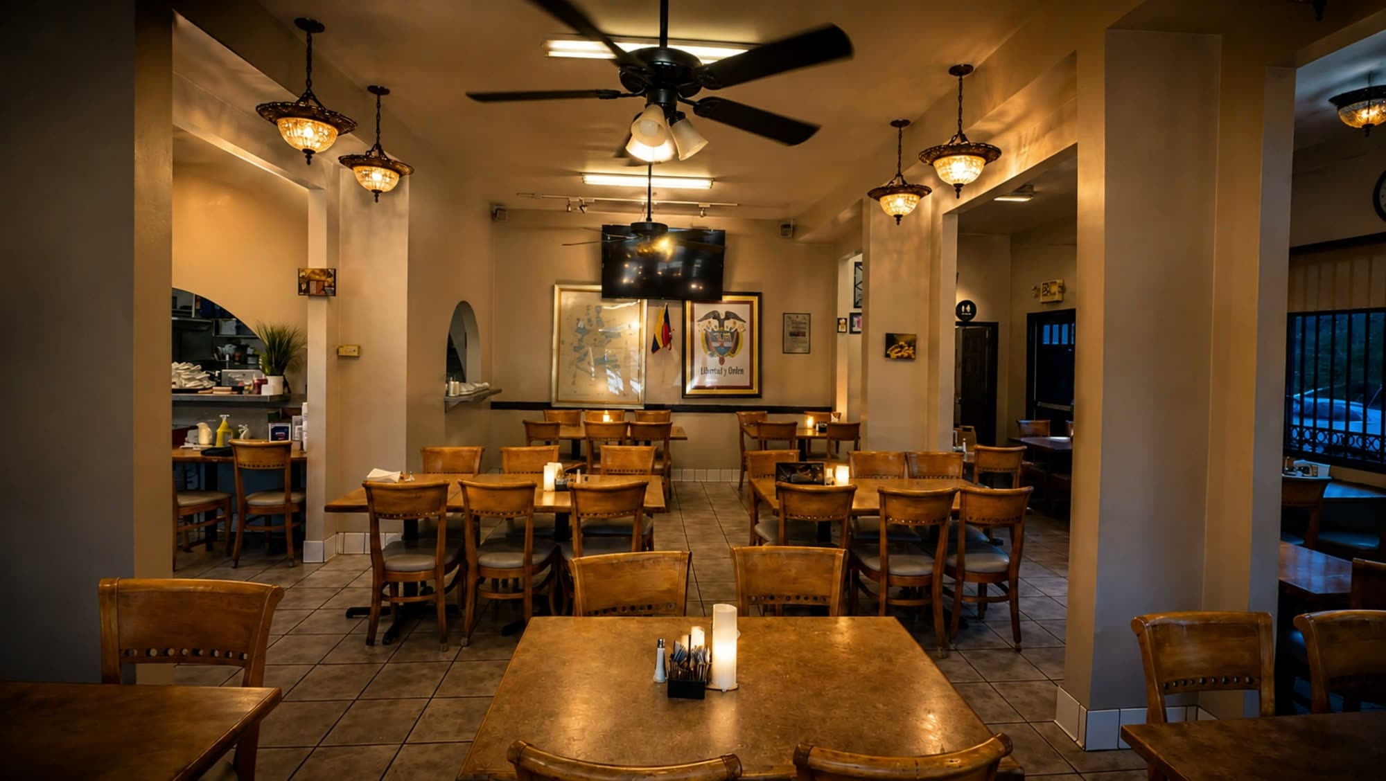 The dining room at La Fonda Antioqueña — wooden tables, warm chandeliers and the La Fonda placard on the wall